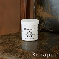 白色圓形罐裝的 Renapur 皮革保養油，罐身印有品牌名稱、皮革圖標、「Extra Quality」字樣以及「Leather Balsam」產品名稱。罐子放置於深棕色紋理皮革表面上。
