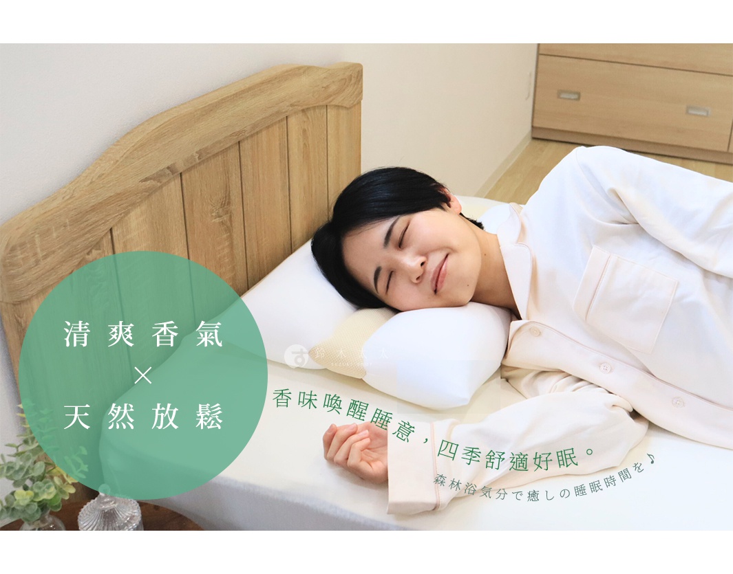 在王樣的檜木清香枕上，一位女子臉上帶著安詳的笑容，眼神閉合，顯然正在享受舒適的睡眠。枕頭散發著清爽的檜木香氣，彷彿置身於森林之中，帶來天然的放鬆感。枕套材質柔軟，搭配著木質床頭板，營造出一種寧靜而溫馨的睡眠氛圍。