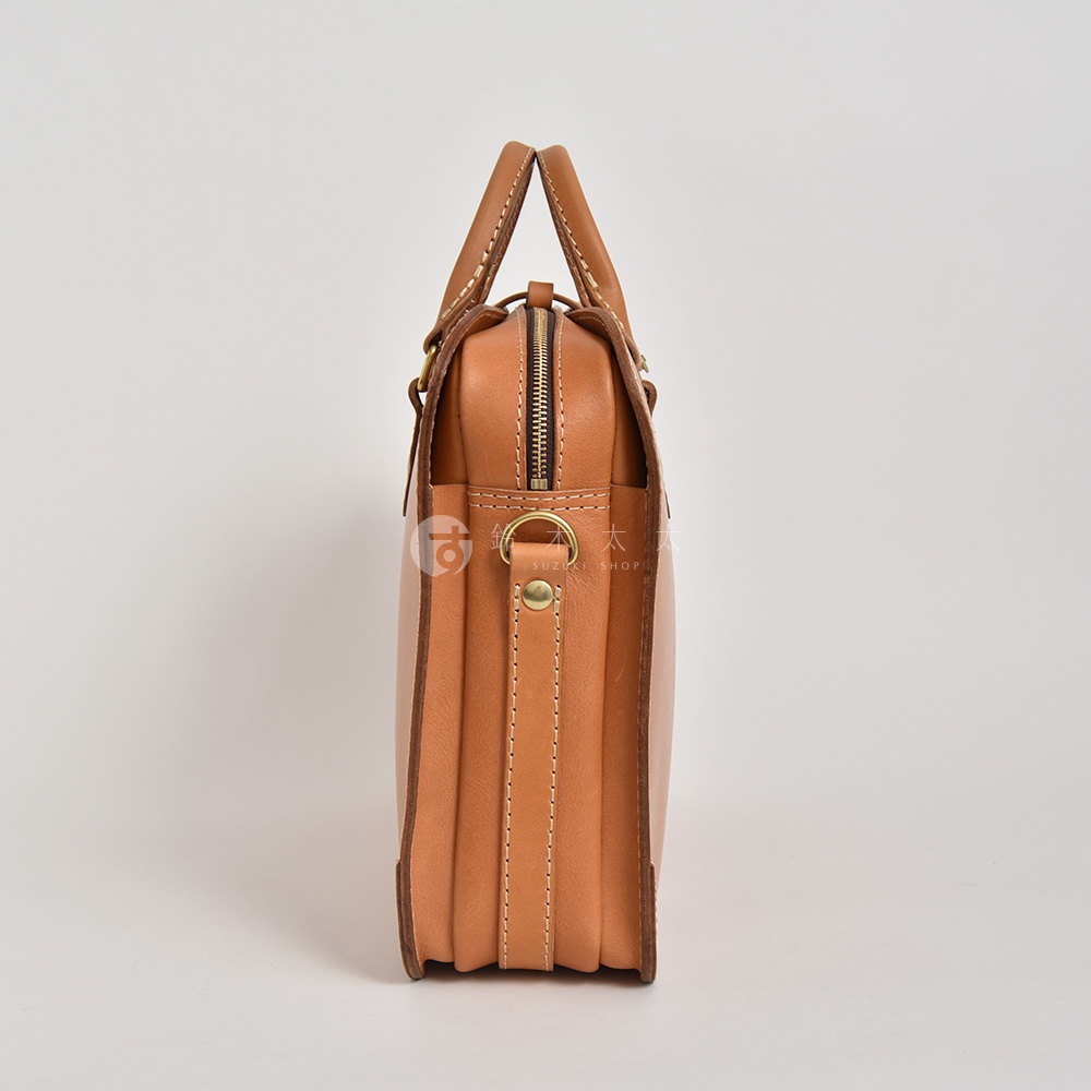 棕褐色皮革製成的手提公事包，側邊視角，展現三層結構設計，配有拉鍊開合、兩個提把及金屬扣環。