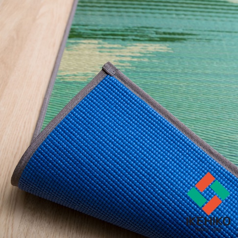 藺草榻榻米瑜珈墊，一面為綠色與米色編織的藺草紋理，另一面為藍色止滑紋理，邊緣為灰色包邊。