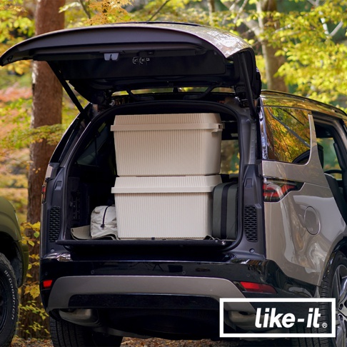 兩個可疊式波浪紋收納箱，淺米色，帶有清晰的垂直凹槽紋理，堆疊在汽車後座。