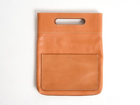 職人手作皮革直式收納袋中袋，顏色為淺棕色，材質為真皮，設計簡約，正面有一個方形外袋，上方有提把孔，縫線清晰。