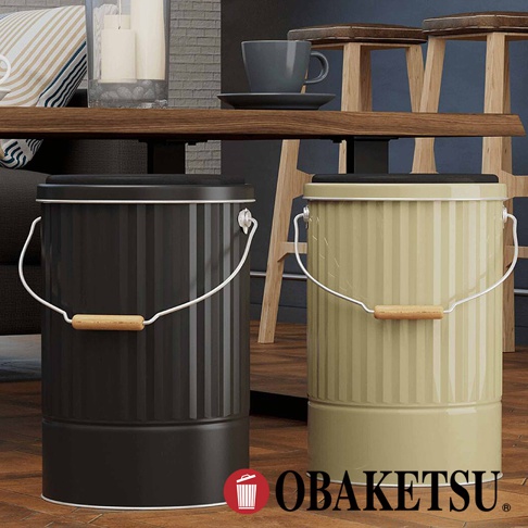 OBAKETSU 雙色對比儲物桶，分別為黑色和米黃色，皆帶有木質把手和金屬提把，整體呈圓筒狀，復古工業風設計。