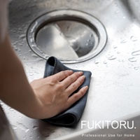 一隻手正用深灰色超細纖維擦拭布擦拭濕漉漉的廚房水槽。