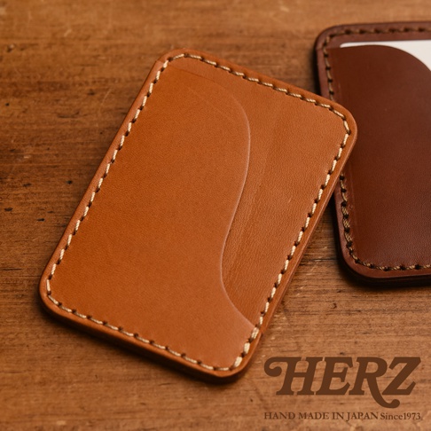 職人手作皮革名片夾，淺棕色皮革配白色縫線，質感細緻，旁邊為深棕色同款名片夾。