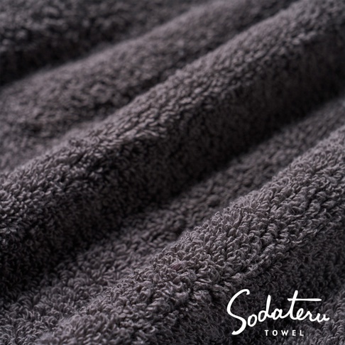 深灰色蓬鬆柔軟的雲感浴巾，材質細緻，紋理清晰，展現其輕盈快乾的特點。