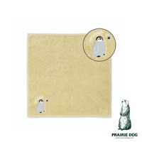 淺黃色毛巾，一角繡有灰色企鵝與藍色星星圖案，並附有放大圖示。右下角有草原犬鼠插畫及品牌名稱 PRAIRIE DOG。