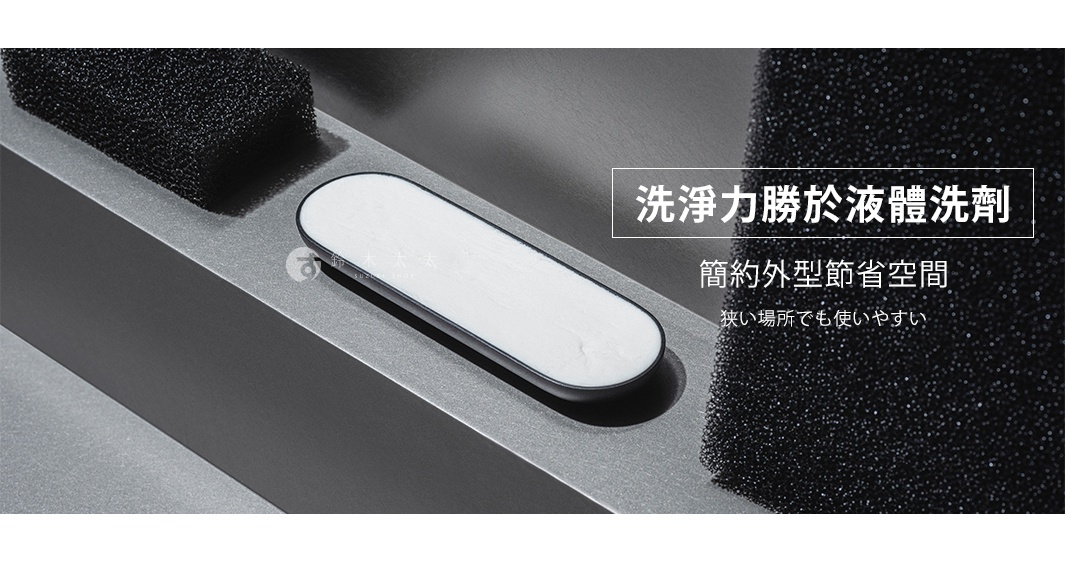 一個橢圓形的白色固體皂置於灰色金屬表面，旁邊有黑色的海綿。