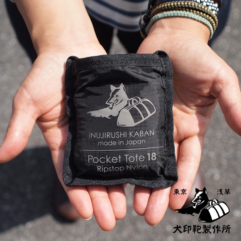 黑色犬印鞄環保折疊收納購物袋，採用 Ripstop Nylon 材質，印有品牌標誌性動物圖案與產品資訊。