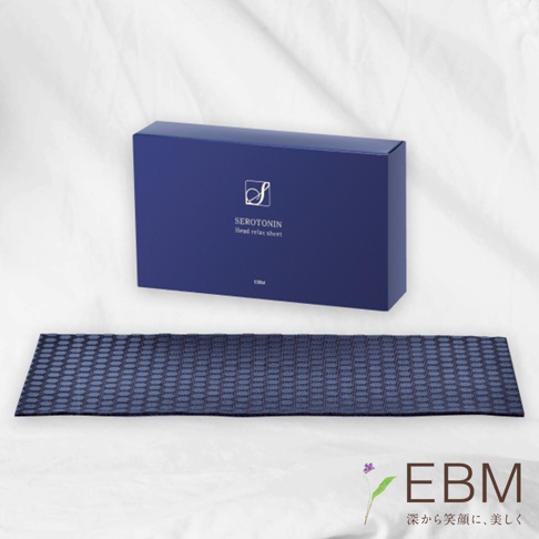 深藍色長方形紙盒，印有金色「S」標誌及「SEROTONIN Head relax sheet」字樣，下方擺放著一條同色系、表面有網格紋路的長條形墊片。