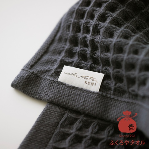 深灰色格紋織物的特寫，標籤上印有和紙棉紡字樣
