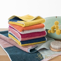 一疊純棉毛巾，呈現玩轉色塊的混色設計，包含黃色、橘色、粉色、紫紅色、藍色與綠色等，質感柔軟。
