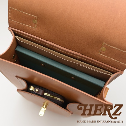 職人手作皮革復古後背包，展示內部空間，可見淺棕色皮革材質，內有筆記本、文件夾，以及一個黑色拉鍊零錢包。