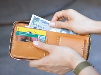 職人手作皮革全包式拉鍊短夾，淺棕色皮革，拉鍊為金色，內有鈔票、信用卡及名片。