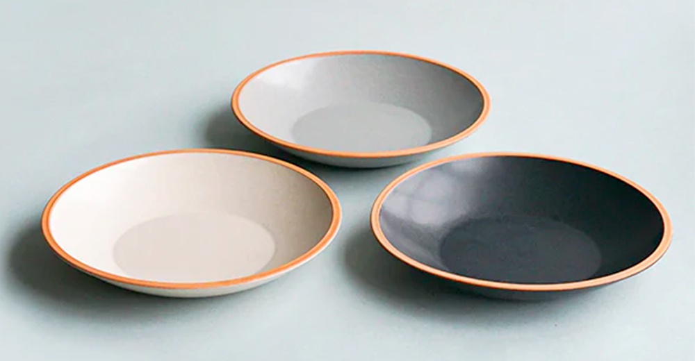 三只素燒陶瓷義大利麵盤，分別為淺灰、米白和深灰色，皆帶有裸色寬邊，呈現簡約風格。