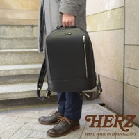 黑色皮革立體商務後背包，配有金色拉鍊和金屬扣環，由日本職人手工製作。