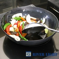 極PREMIUM不易生鏽炒鍋 (30cm)，黑色鐵鍋中盛滿各種新鮮蔬菜，包括紅甜椒、荷蘭豆、紅蘿蔔、洋蔥、香菇等，鍋內有少量烹調用油，一把銀色金屬鍋鏟置於鍋中。