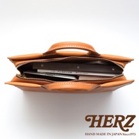 HERZ 職人手作皮革公事包，棕色皮革材質，俯視視角，展示包內物品。