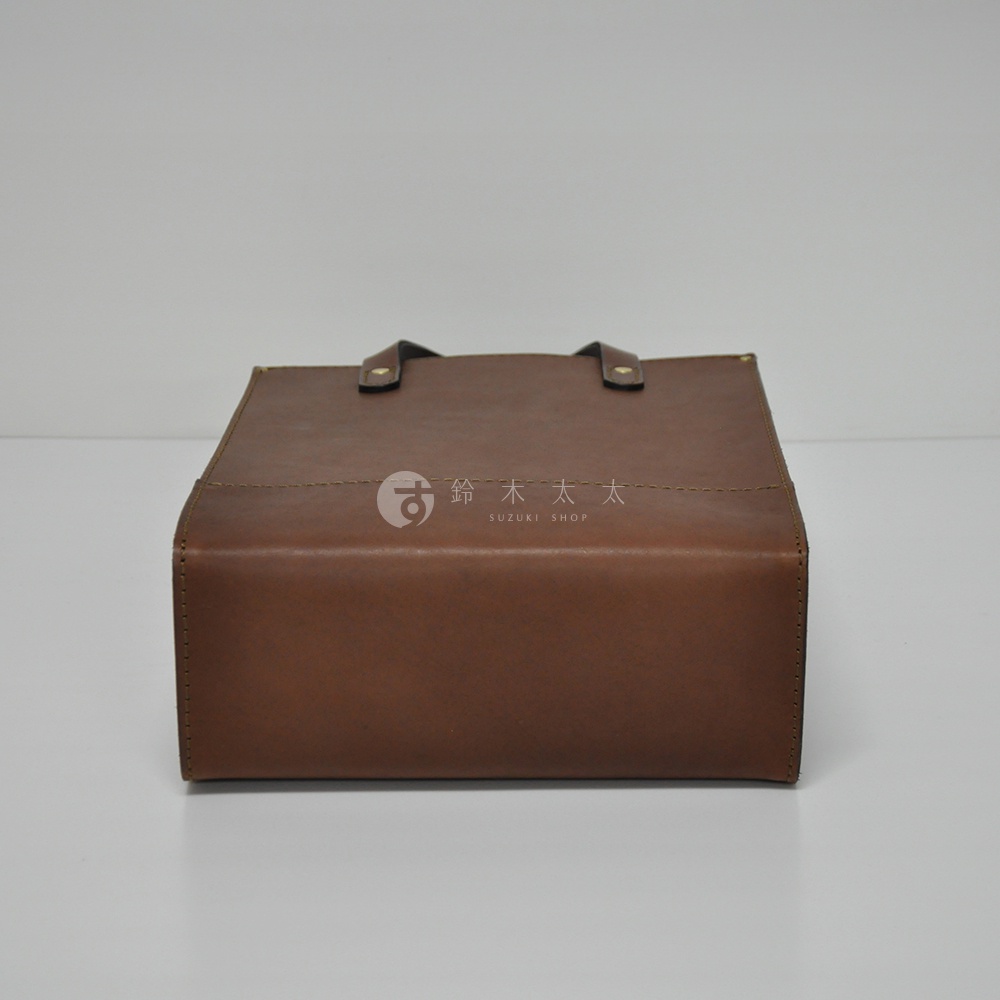 深棕色皮革製成的直式托特包，包身方形，兩側有提把，包面有縫線裝飾。