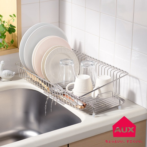 不鏽鋼製長形瀝水籃，內有堆疊的白色、淺粉色和灰色盤子，以及兩個透明玻璃杯和兩個白色馬克杯，置於廚房水槽上方，籃架底部有排水孔。