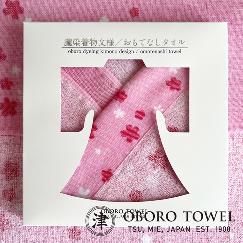 朧染和紋款待之心紗布毛巾，粉色系，帶有櫻花圖案，包裝盒上有日文和英文說明「oboro dyeing kimono design / omotenashi towel」。