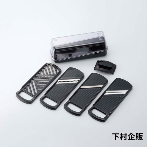 四合一刨絲器，包含一個黑色收納盒、一個黑色刀片保護蓋，以及四個不同刀片的黑色塑膠刨絲板，其中三個刨絲板帶有金屬刀片，刀片上可見白色條紋。