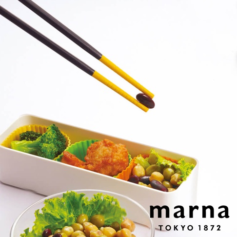 一雙黃色和黑色長筷子夾著一顆深棕色食物，上方是白色背景，下方是一個白色便當盒，裡面裝有西兰花、炸物、豆子和生菜。右下角有「marna TOKYO 1872」的文字。