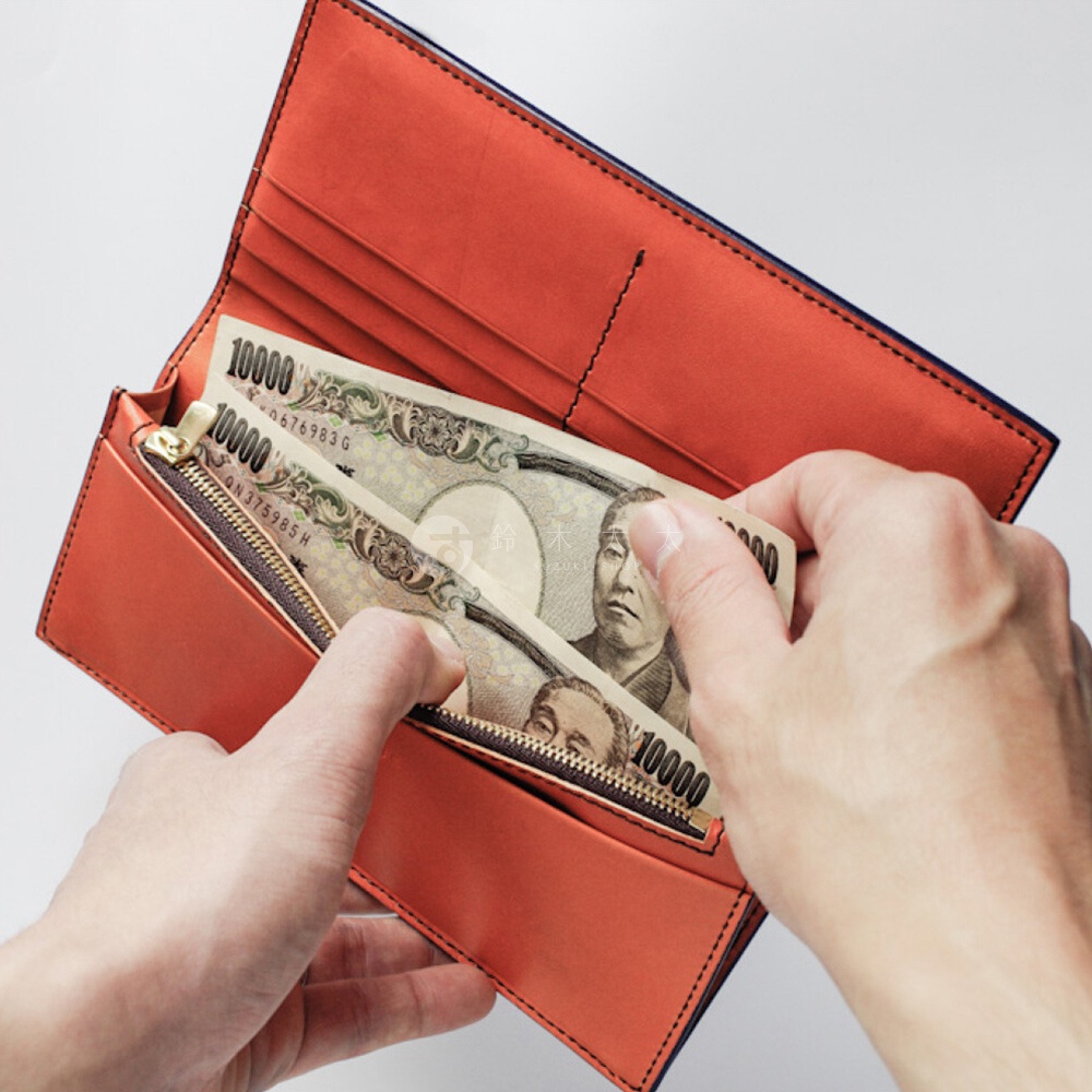 將日圓紙鈔從橘色皮革長夾中取出