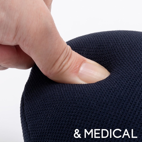 手指按壓深藍色織物材質的肩頸按摩紓壓枕，展現其柔軟回彈的特性。