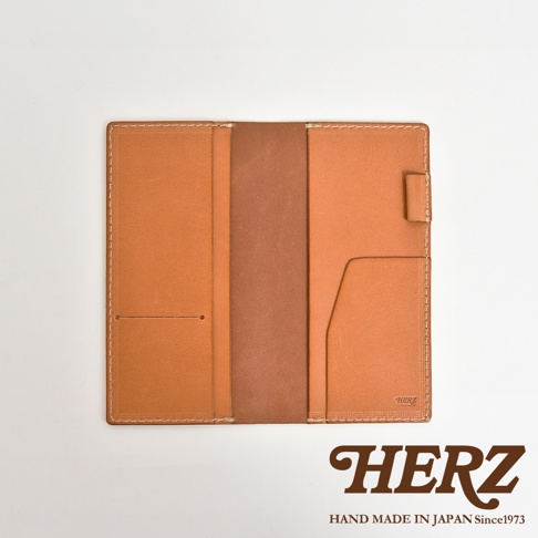 職人手作皮革旅行記事本書套，採用淺棕色牛皮製成，內有隔層與卡槽，以白色縫線裝飾，右側邊緣有皮革束帶。