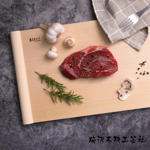 淺色木質砧板上有生牛肉、迷迭香、大蒜、蘑菇和胡椒粒，右上角有一條格紋餐巾和叉子。