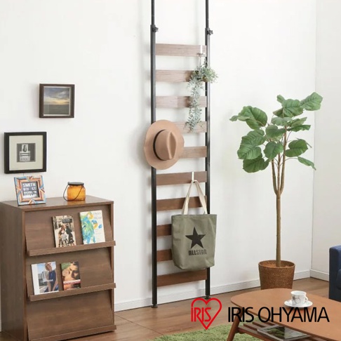 頂天立地收納掛架，黑色金屬支架搭配木紋層板，掛有駝色圓帽、綠色帆布包及盆栽，層板間距約為30公分，整體呈現簡潔實用的設計風格。