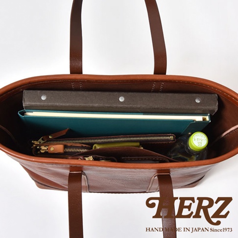 職人手作皮革經典托特包 T-9 M，棕色皮革，內部裝有筆記本、文件夾、錢包和水瓶。