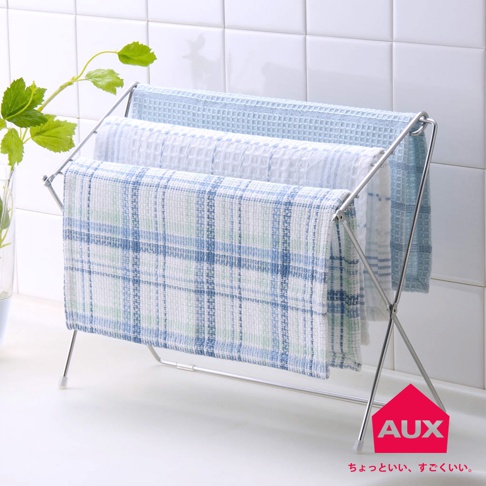 銀色金屬折疊式小物晾曬架，架上掛有三條不同圖案的毛巾：頂部為淺藍色格紋，中間為白色條紋，底部為藍綠色格紋。