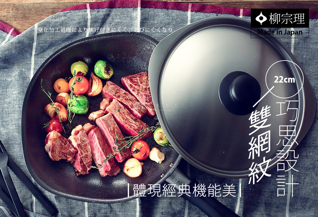 圖片文字：柳宗理 Made in Japan 窒化加工處理，不易沾黏且不易生鏽 22cm 雙網紋 巧思設計 體現經典機能美 一張俯拍的照片，展示了柳宗理品牌的 22 公分雙網紋單手鐵鍋，鍋中正煎烤著牛排與時蔬。鐵鍋表面有特殊的紋理設計，旁邊放著配套的金屬鍋蓋。整體場景放置在灰色格子紋的布料上，呈現出日式經典的廚房機能美感。