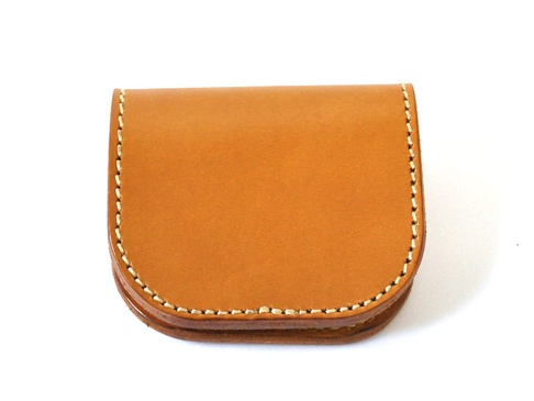 職人手作皮革馬蹄造型零錢包，採用自然色皮革製成，邊緣以白色縫線滾邊，呈現經典簡約的馬蹄形狀。