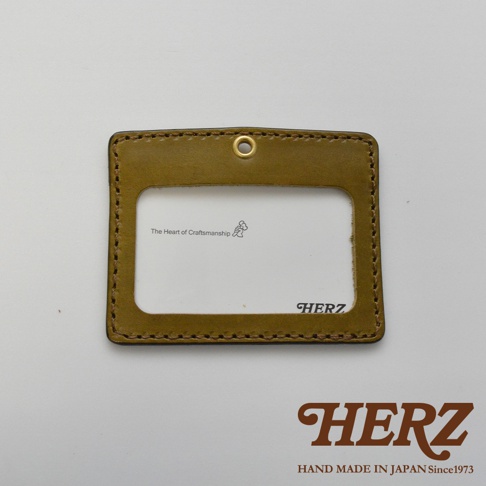橄欖綠皮革橫式證件識別夾，採用職人手作縫製，帶有掛環，夾內有「The Heart of Craftsmanship」及「HERZ」標誌。