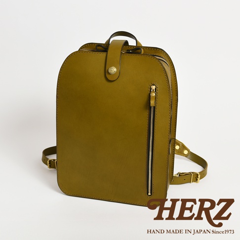 職人手作皮革商務休閒兩用後背包 R-36，橄欖綠色，採用真皮材質，設計簡約，前有拉鍊口袋，頂部有提把及金屬釦設計，可肩背或後背。