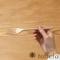 一只手正拿著一個淺色楓木製成的三齒餐叉，餐叉的背景是木紋桌面。