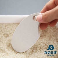 由手持的NANOLABO UB米之守護神珪藻土防潮塊，放入裝滿米的白色容器中，產品上有日文與英文品牌標識。