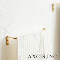 黃銅單桿毛巾架，表面光滑，金屬光澤，固定於白色紋理牆面，懸掛一條白色素面毛巾。