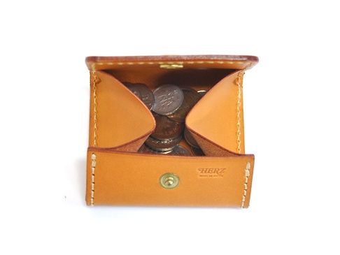 職人手作皮革箱型收納零錢包，淺棕色牛革材質，內有硬幣，包身縫線清晰，正面中央有黃銅按扣及品牌壓印。
