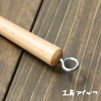 VEGET 不鏽鋼木柄削皮刀，特寫木質手柄末端，連接金屬掛環，背景為深色木紋桌面。