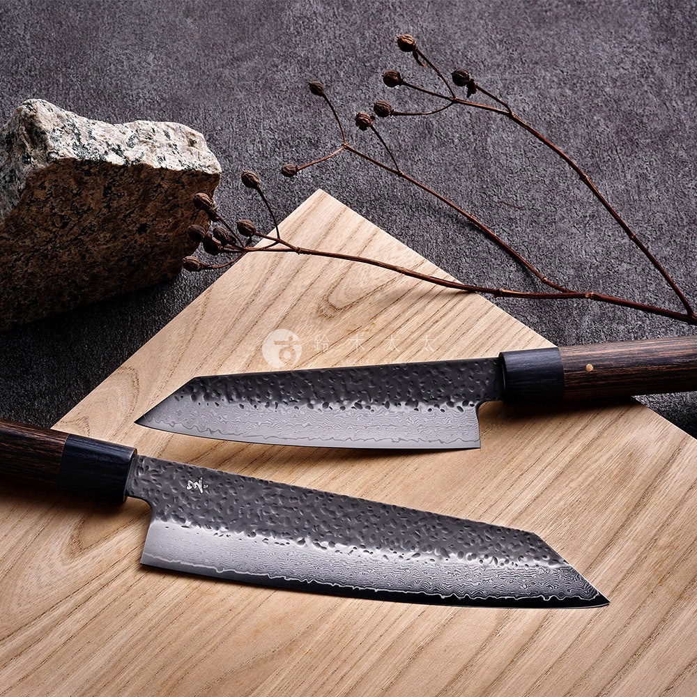 兩把帶有槌紋和木質手柄的日式廚刀，擺放在木質砧板上，背景是灰色石板和乾燥的樹枝。