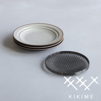 一疊淺色美濃燒餐盤，盤緣帶有深色線條，旁邊放著一個全黑的瀝油網。