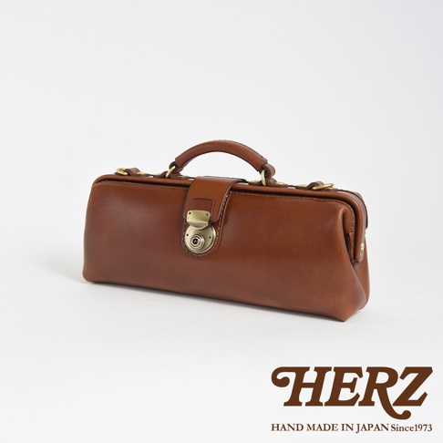 HERZ 職人手作皮革橫長形杜勒斯單肩包，展示品牌標誌與「HAND MADE IN JAPAN Since1973」字樣