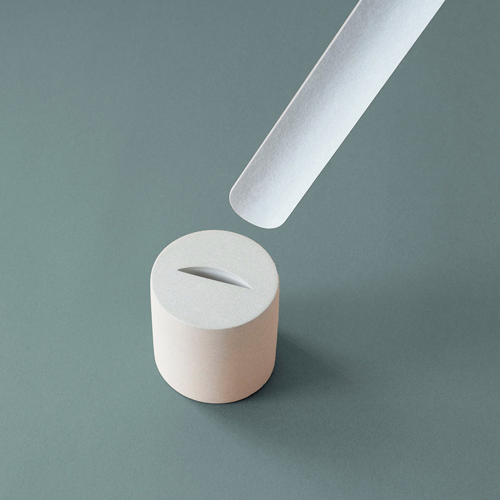 簡約的白色鞋拔，搭配米色圓柱形底座，底座頂部有長形縫隙，整體呈現代設計風格。