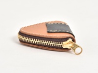 棕色皮革製成的三角形零錢包，帶有深棕色皮革飾邊和黑色皮革裝飾，金色拉鍊。