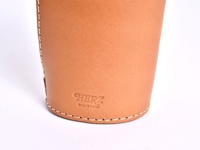 淺棕色皮革製成的直立式筆袋，表面壓印有「HERZ」品牌標誌及「MADE IN JAPAN」字樣，邊緣以白色縫線裝飾。