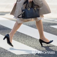 一位女性穿著黑色亮面高跟鞋，跨越斑馬線，腳上搭配著鞋墊式暖暖包。